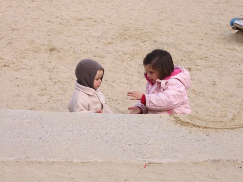 Girl teaching her little brother how play in the sandbox